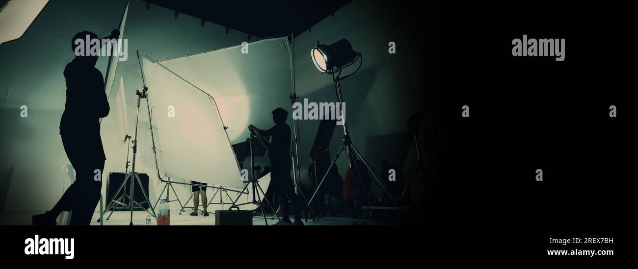 Silhouette de production vidéo en coulisses ou B roll ou réalisation de films publicitaires télévisés que l'équipe de tournage lightman et caméraman travaillent ensemble Banque D'Images