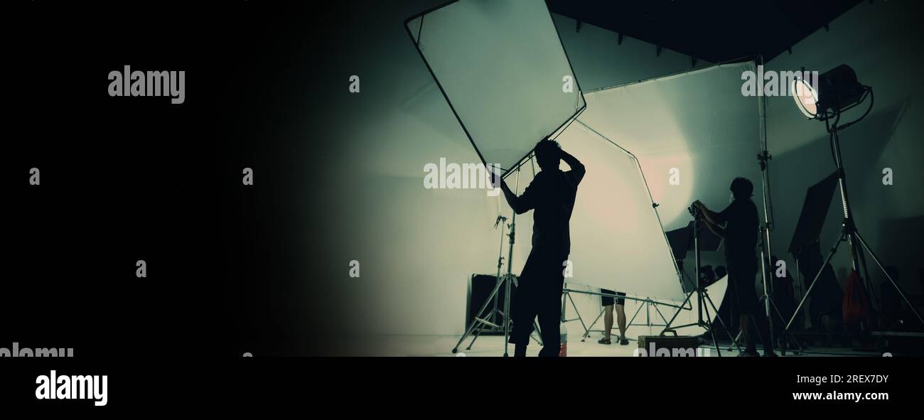 Silhouette de production vidéo en coulisses ou B roll ou réalisation de films publicitaires télévisés que l'équipe de tournage lightman et caméraman travaillent ensemble Banque D'Images