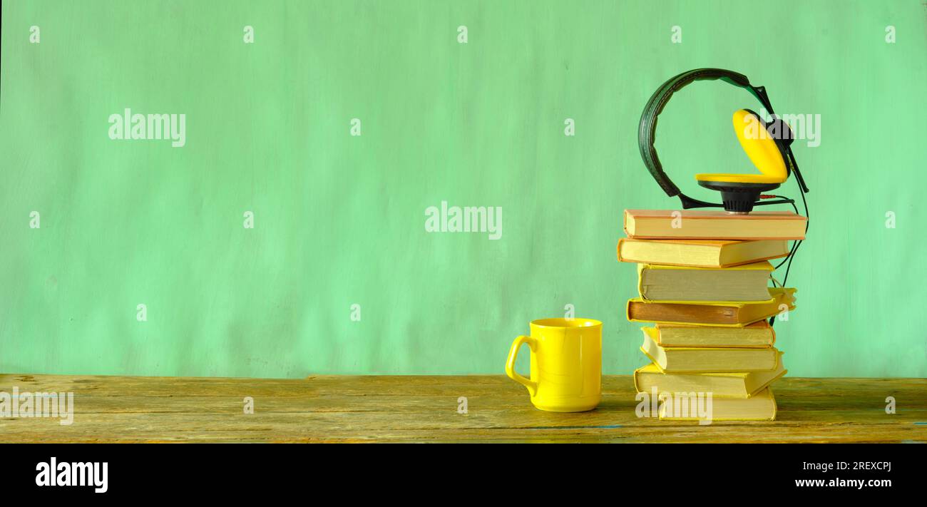 concept de livre audio avec pile de livres et écouteurs vintage sur fond de peinture vert pastel, bon espace de copie, panoramique Banque D'Images