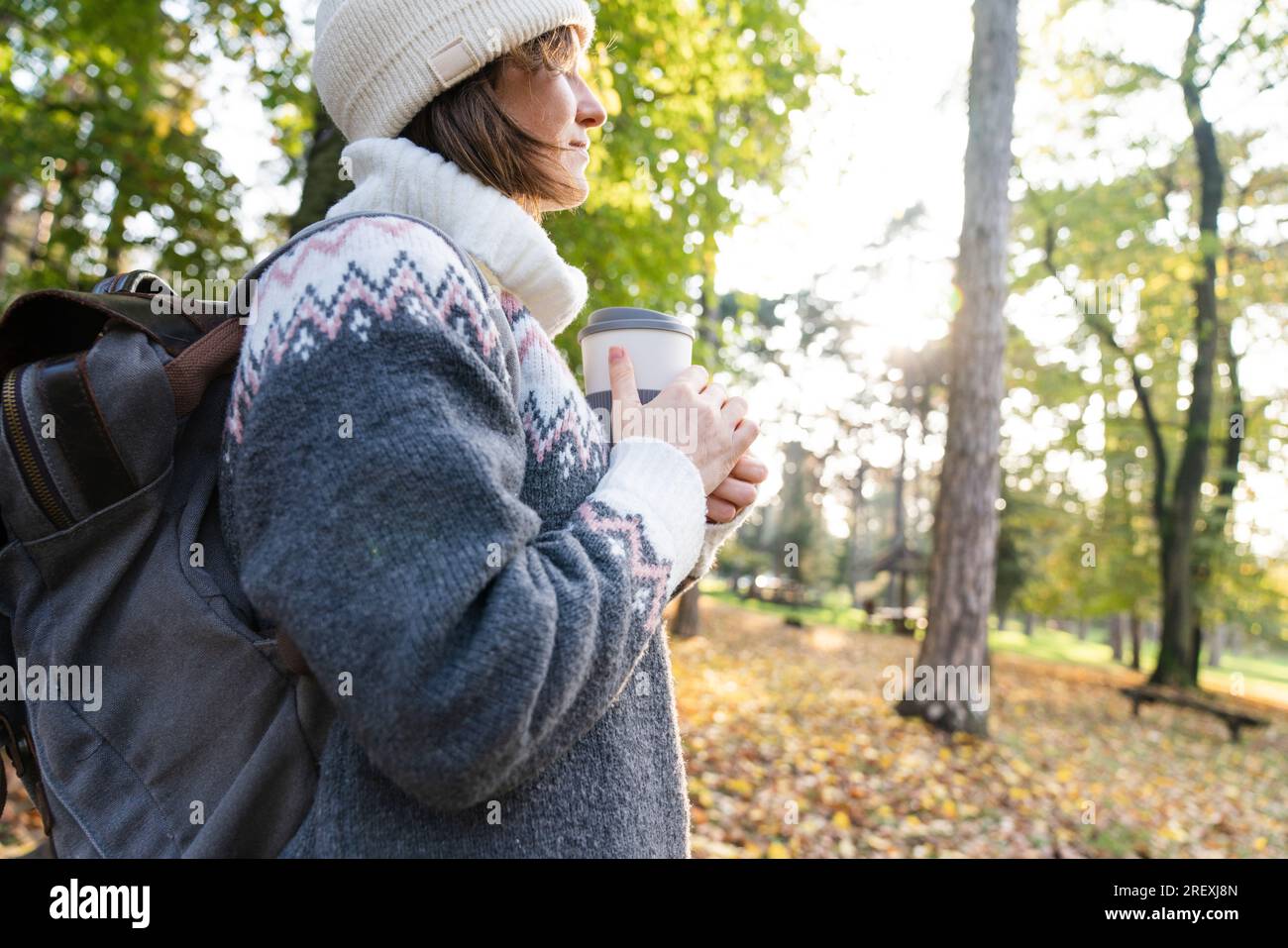 Femme voyageur avec sac à dos tient une tasse de boisson chaude dans le parc d'automne. Banque D'Images