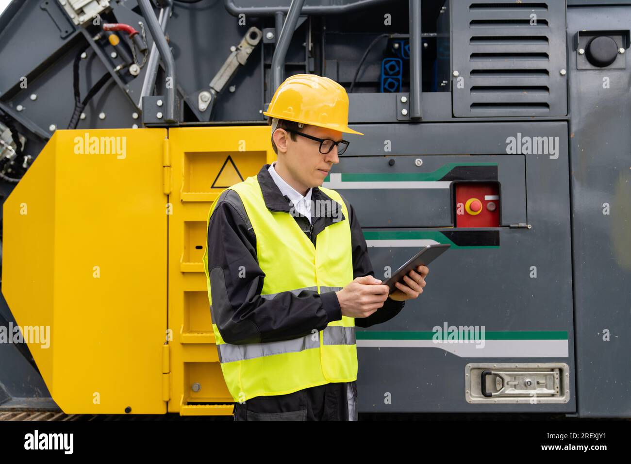 Concevoir avec une tablette numérique à côté de la machine de construction routière. Banque D'Images