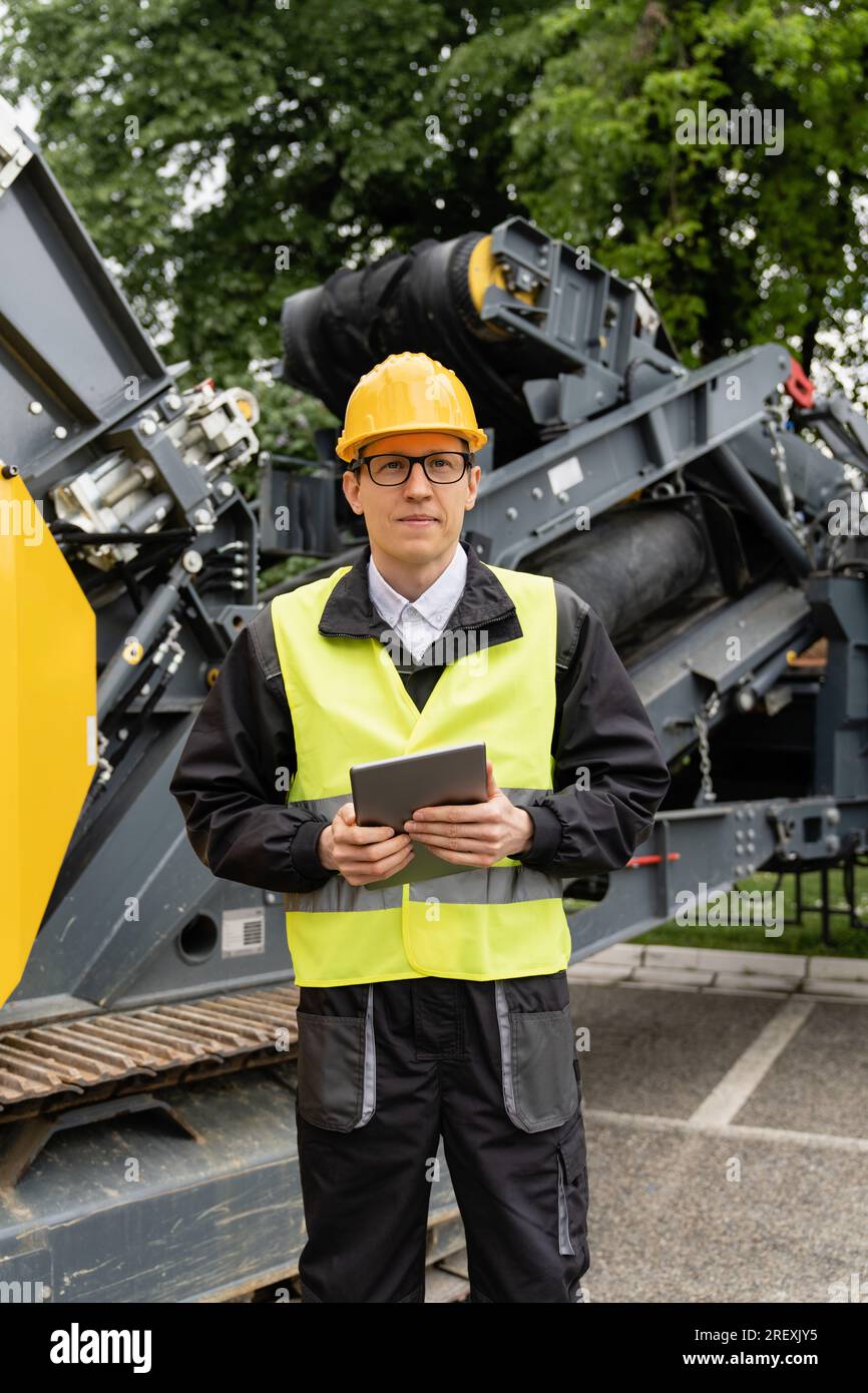 Concevoir avec une tablette numérique à côté de la machine de construction routière. Banque D'Images
