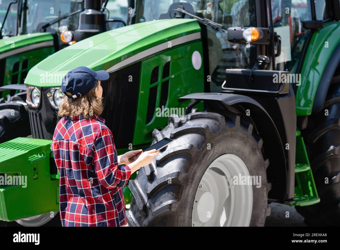 Femme agricultrice avec une tablette numérique sur le fond d'un tracteur agricole.. Banque D'Images