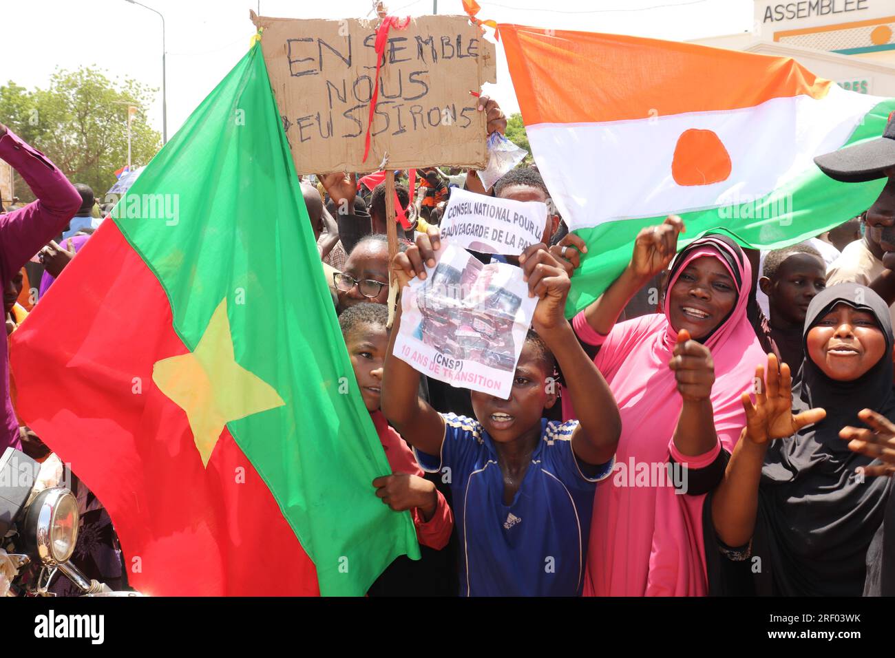 Niamey, Niger. 30 juillet 2023. Les Nigériens tenant un drapeau du Burkina Faso (l) et du Niger et une pancarte indiquant "ensemble, nous le ferons" participent à une marche convoquée par les partisans du général Omar Tchianis. Après le coup d’État au Niger, des milliers de personnes ont promis leur soutien à l’armée. Crédit : Djibo Issifou/dpa/Alamy Live News Banque D'Images