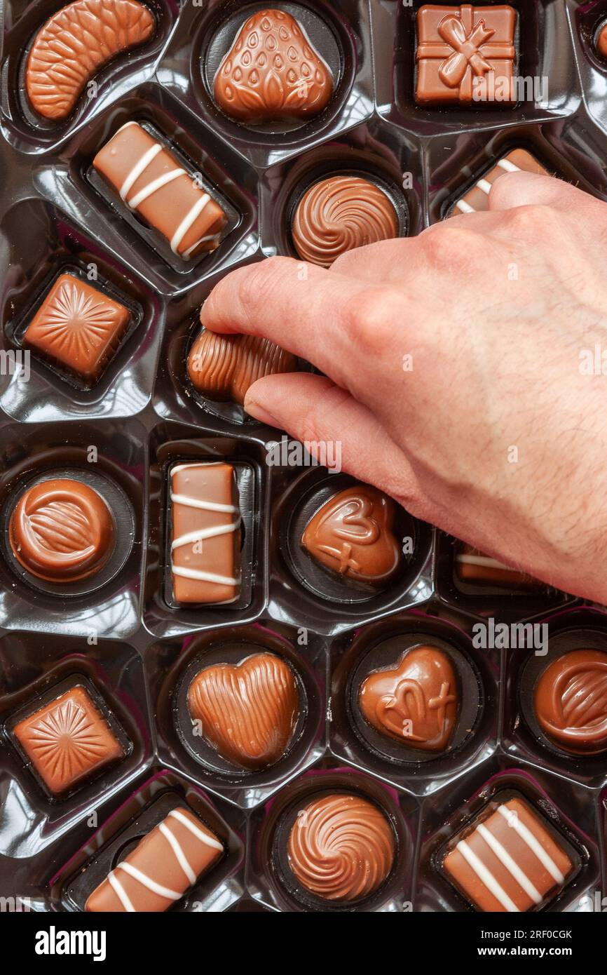 Une main choisissant un chocolat dans une boîte de chocolats de Cadbury 'Milk Tray'. Banque D'Images