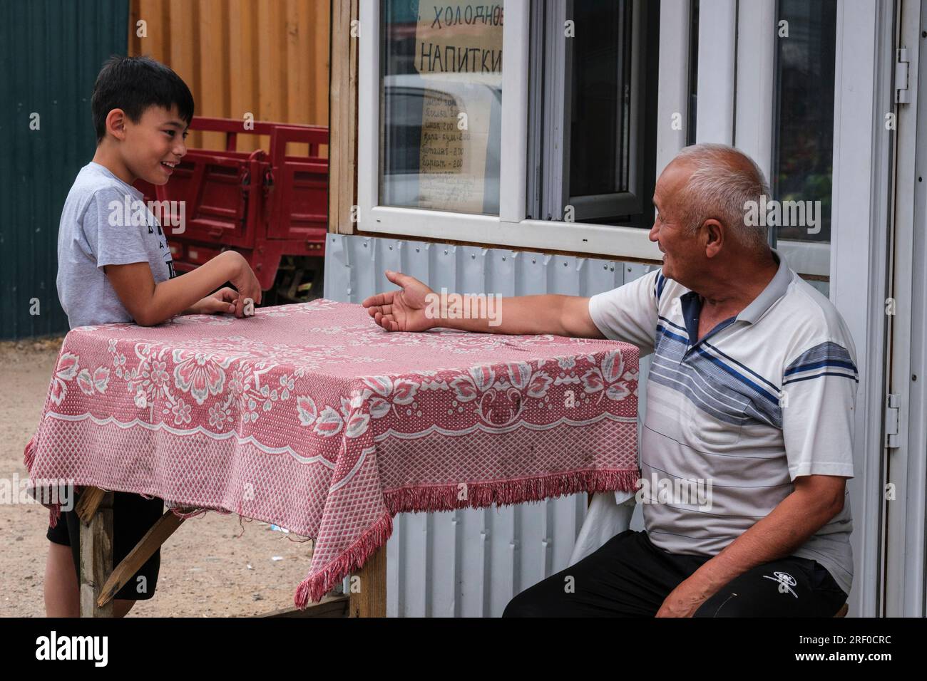 Kazakhstan, Bayseit. Homme âgé et jeune garçon parlant. Banque D'Images