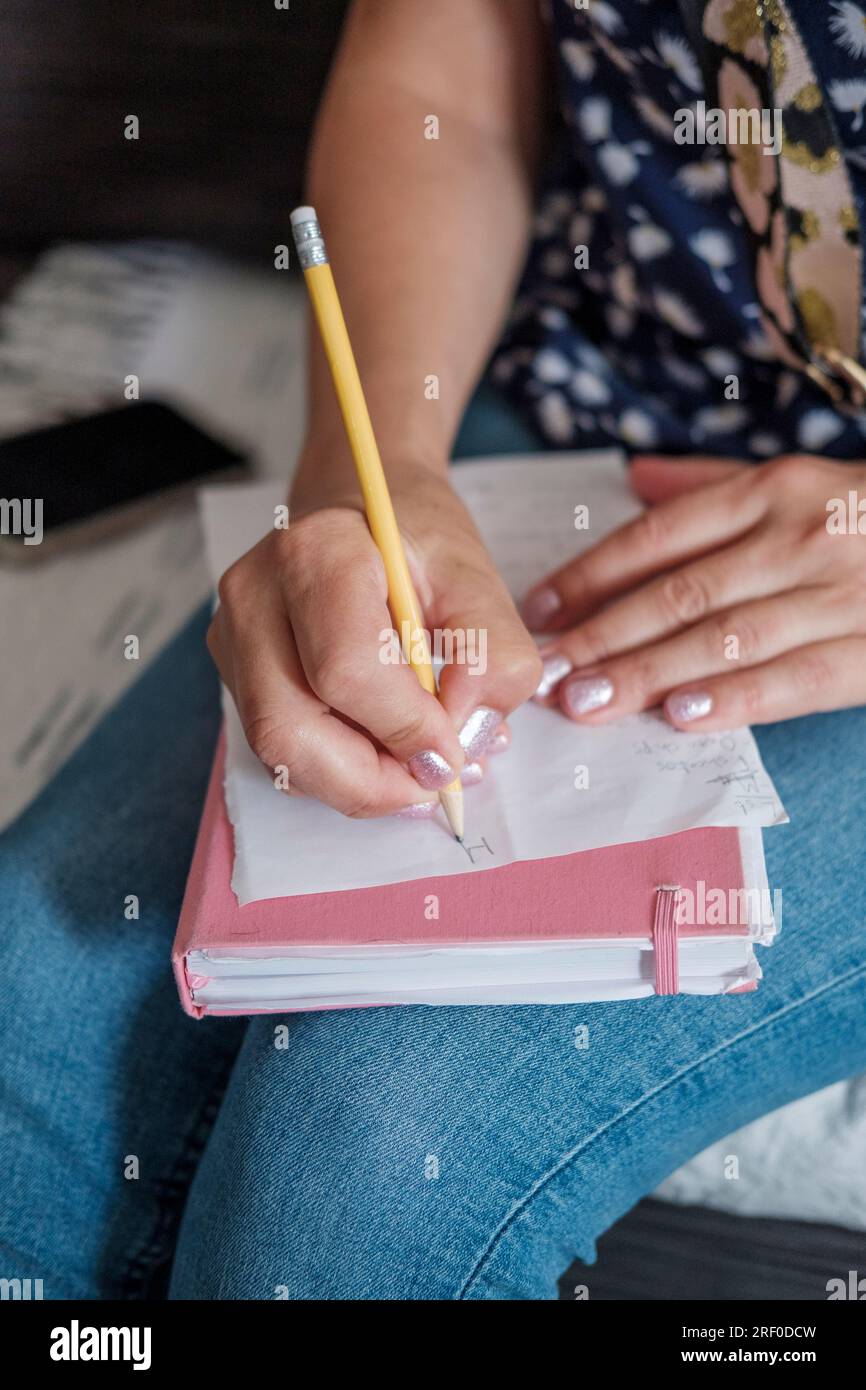 Femme écrit une liste sur ses courses au tour-quotidien, liste de courses Banque D'Images