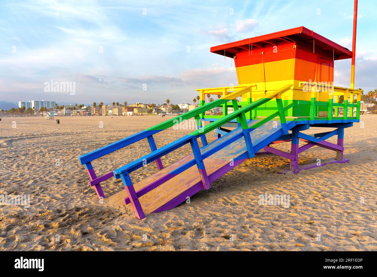Tour de sauveteur peinte en arc-en-ciel avec en toile de fond une ville animée. L'essence de la destination balnéaire emblématique de Californie. Banque D'Images