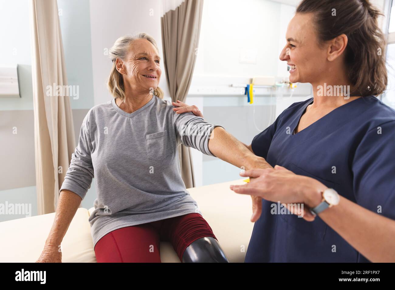 Femme caucasienne physiothérapeute et femme âgée avec bras de massage de jambe artificielle à l'hôpital Banque D'Images