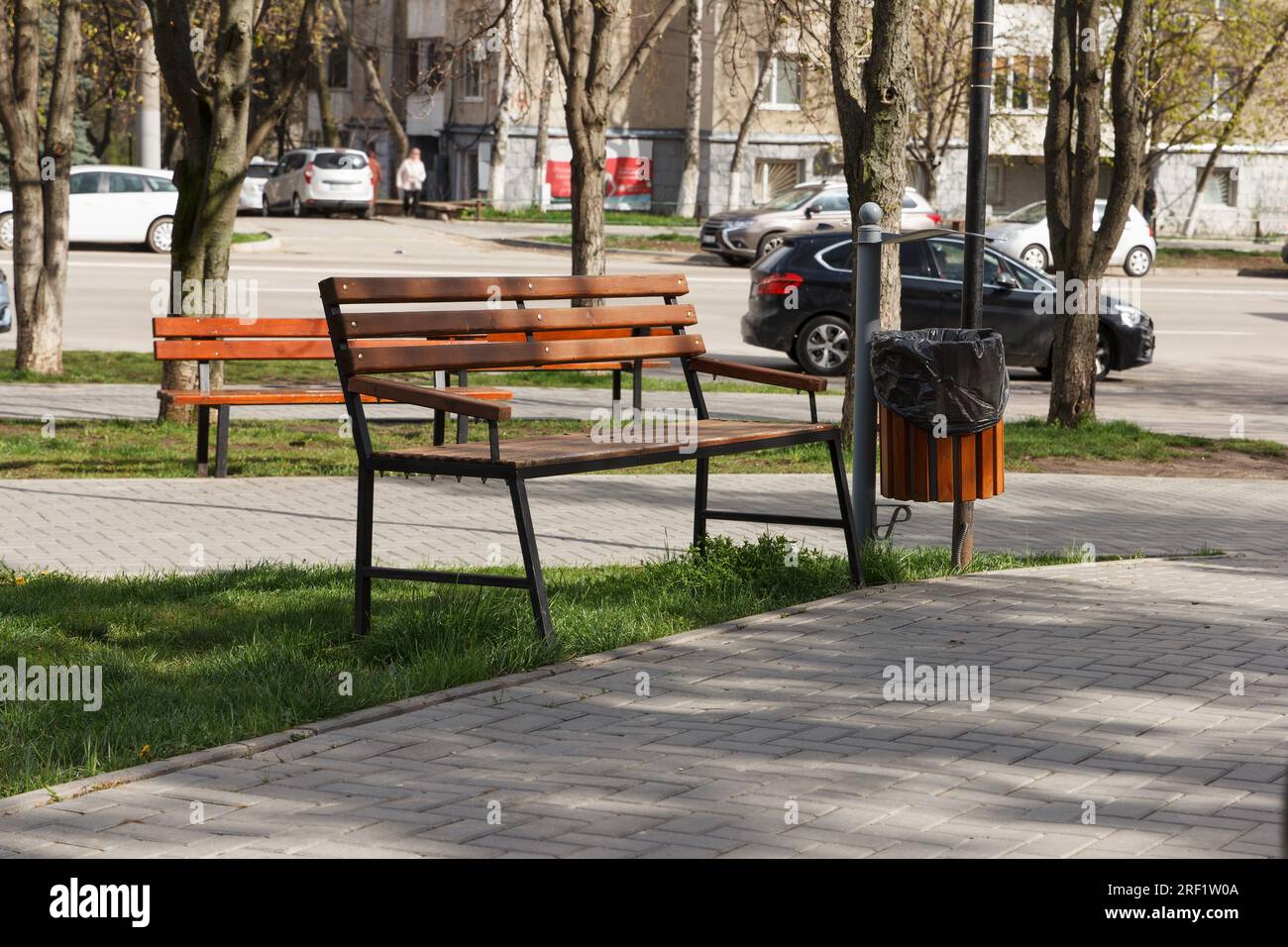 Une poubelle avec un sac poubelle est installée dans un lieu public, un parc. Situé à proximité du banc en bois et du trottoir Banque D'Images