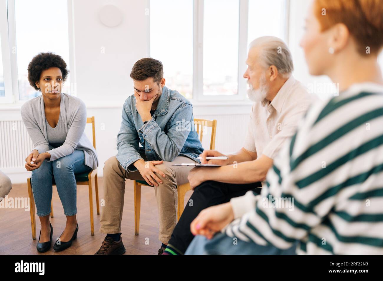 Vue latérale du chef de groupe adulte senior sérieux parlant lors de la réunion de teambuilding. Équipe d'affaires assis sur des chaises en cercle, parlant, discutant Banque D'Images