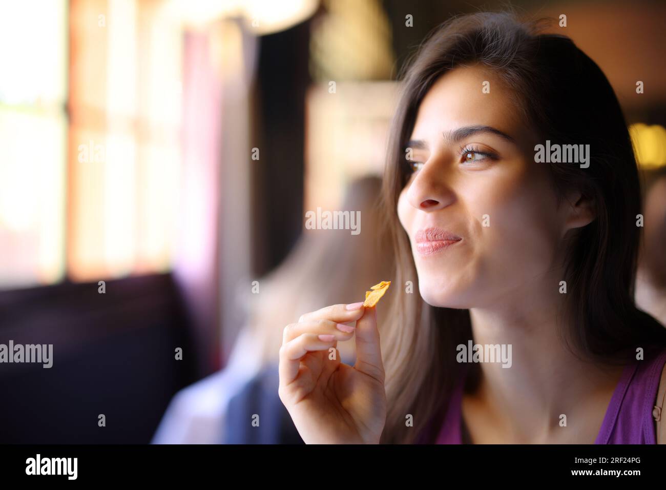 Client heureux du restaurant mangeant des chips regardant loin Banque D'Images