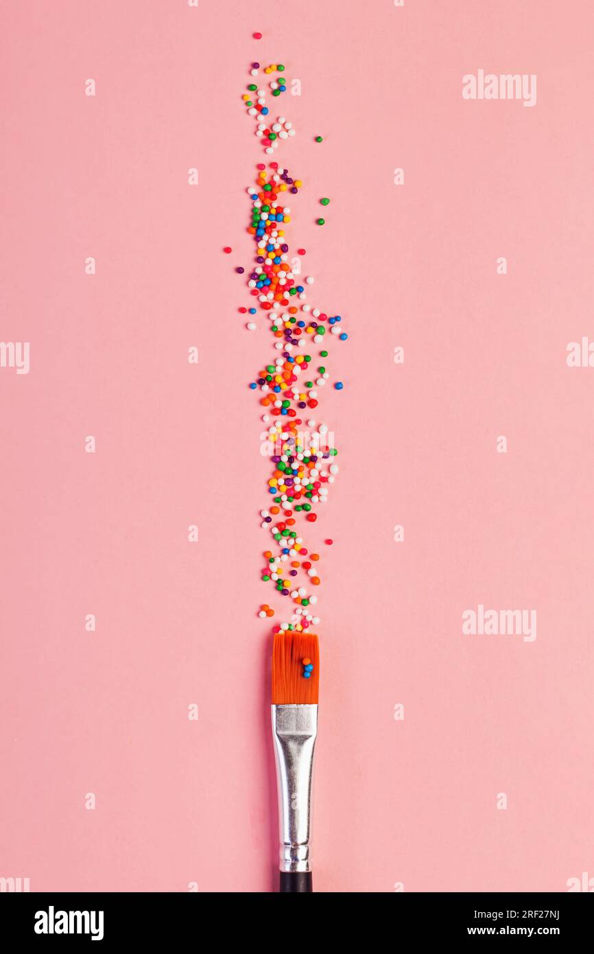 Saupoudrages de sucre en forme d'étoile et pinceau sur fond rose pastel, concept d'art et de créativité Banque D'Images