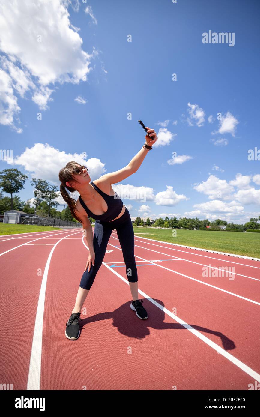 fit jeune femme prend selfie avec téléphone tout en faisant du jogging sur une piste Banque D'Images