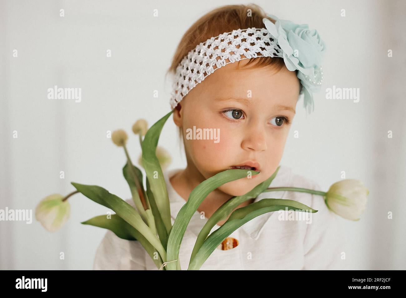 Douce fille en bas âge avec bouquet de fleurs dans les mains. Banque D'Images