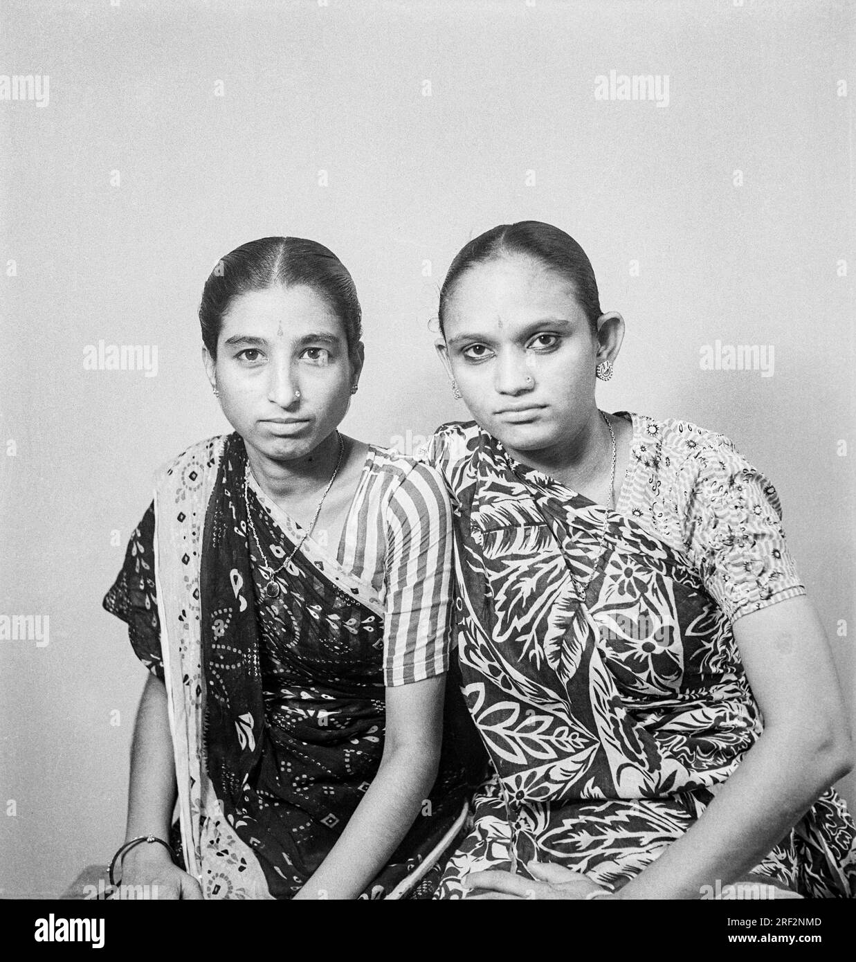 Vieux vintage des années 1900 photo de studio noir et blanc de sœurs jumelles indiennes portant Saree India 1940s. Banque D'Images