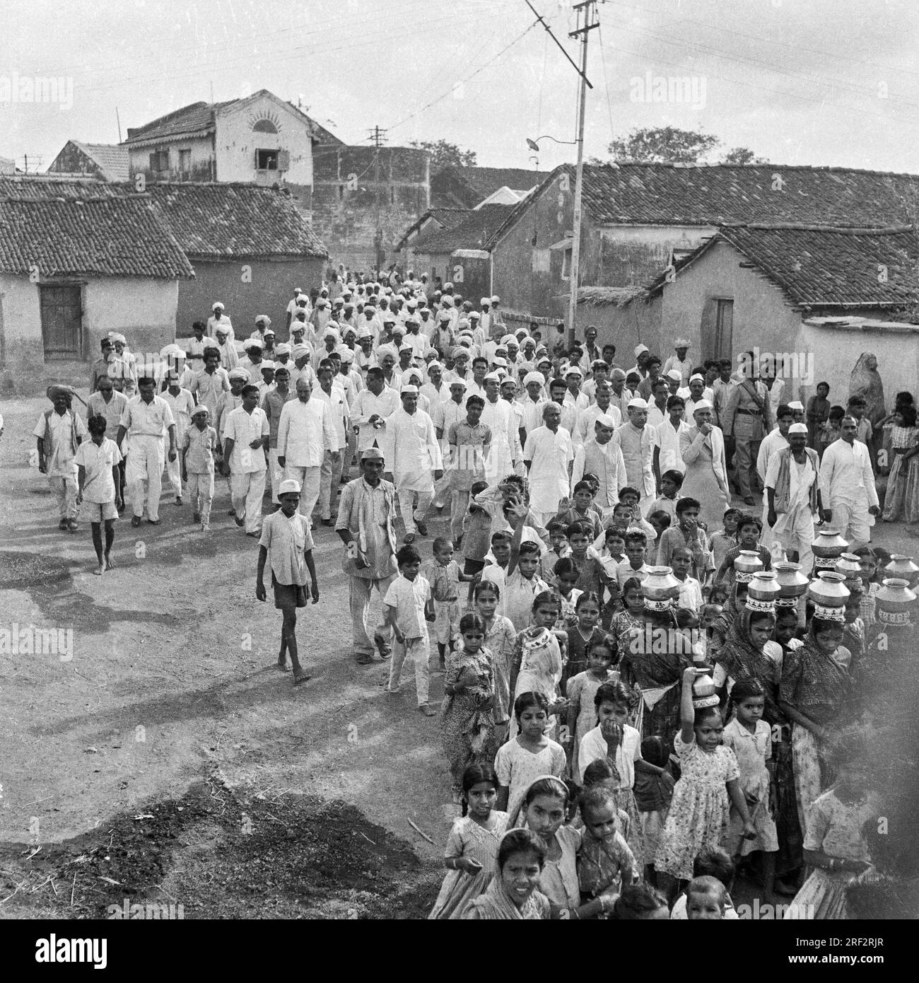 Vieux vintage des années 1900 photo en noir et blanc de procession religieuse de village, femmes portant des pots, hommes portant casquette Gandhi, Inde Banque D'Images