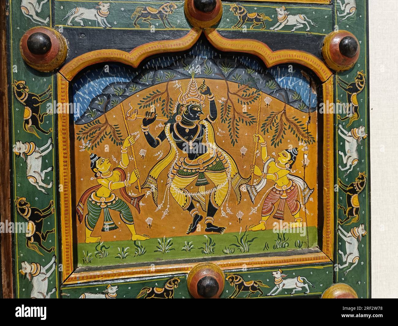 Krishna soulevant la colline de Govardhana avec son petit doigt. Histoires populaires de la vie de Krishna peintes sur une porte. Forme Bhittichitra. Banque D'Images