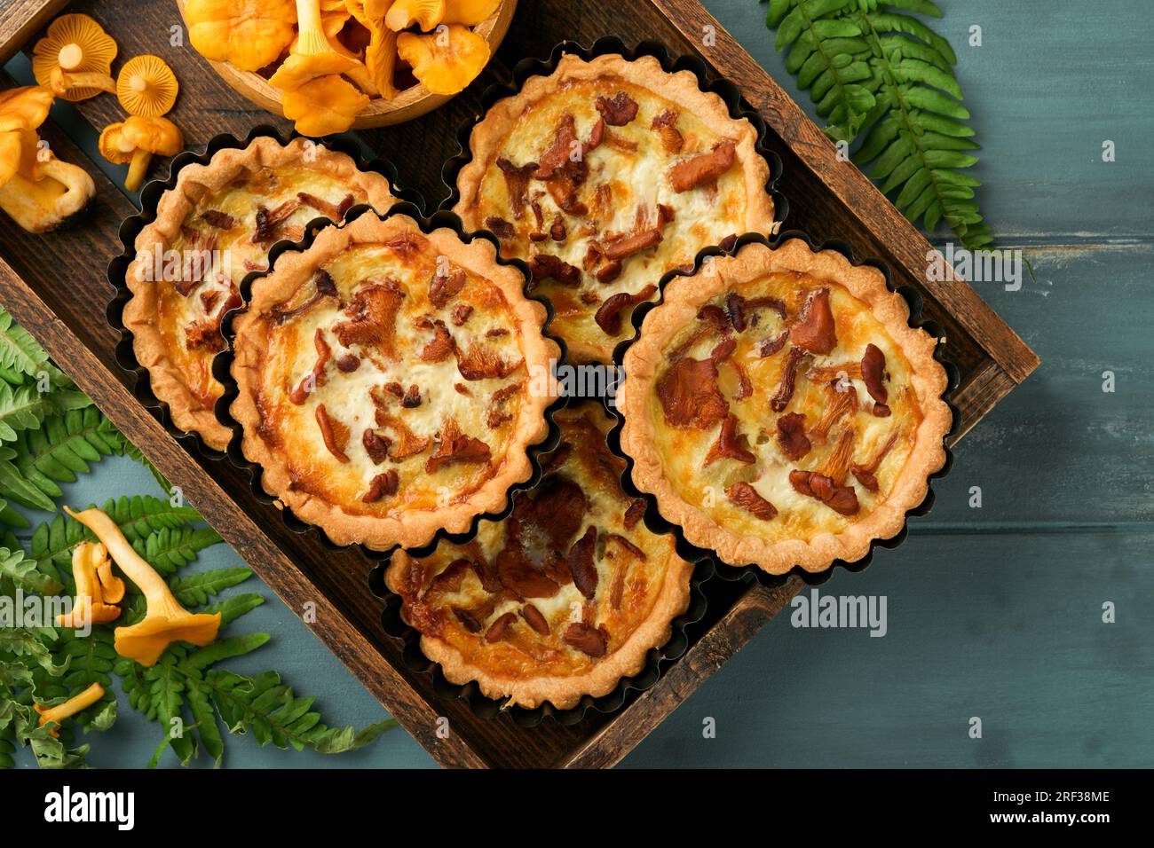 Tarte aux mains savoureuses avec des champignons chanterelles, crème et fromage sur une planche à découper sur fond de table en bois rustique. Tartes maison avec cha de saison Banque D'Images