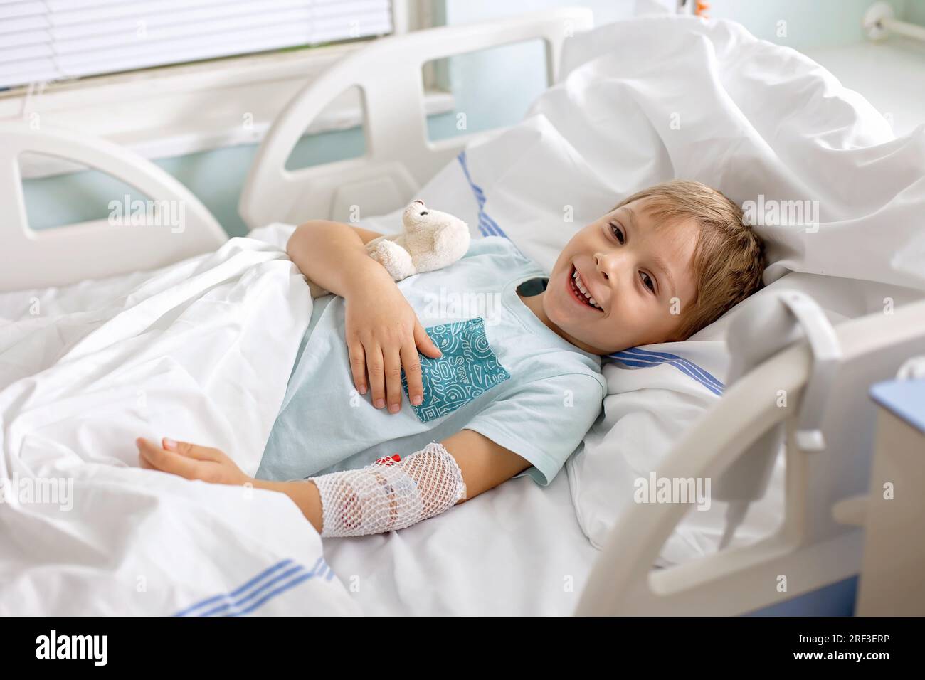 Petit enfant d'âge préscolaire, allongé à l'hôpital après un accident, mère l'accompagnant Banque D'Images