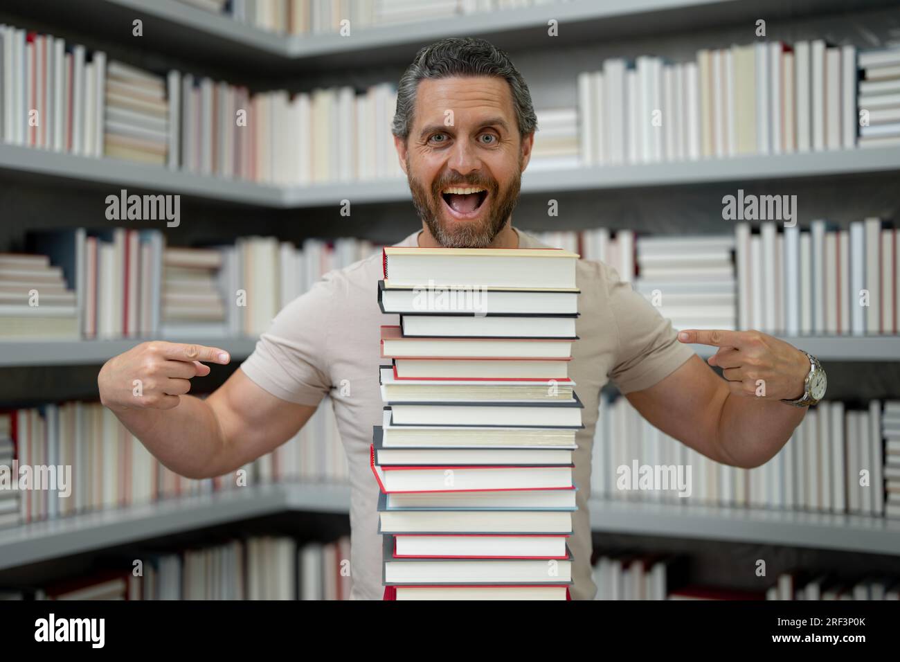 Drôle d'enseignant de tenir beaucoup de livres. Professeur fou avec des livres. Enseignant enthousiaste dans la bibliothèque de livres de l'école. Examen universitaire. Étudier enseigner à l'université. Éducateur Banque D'Images