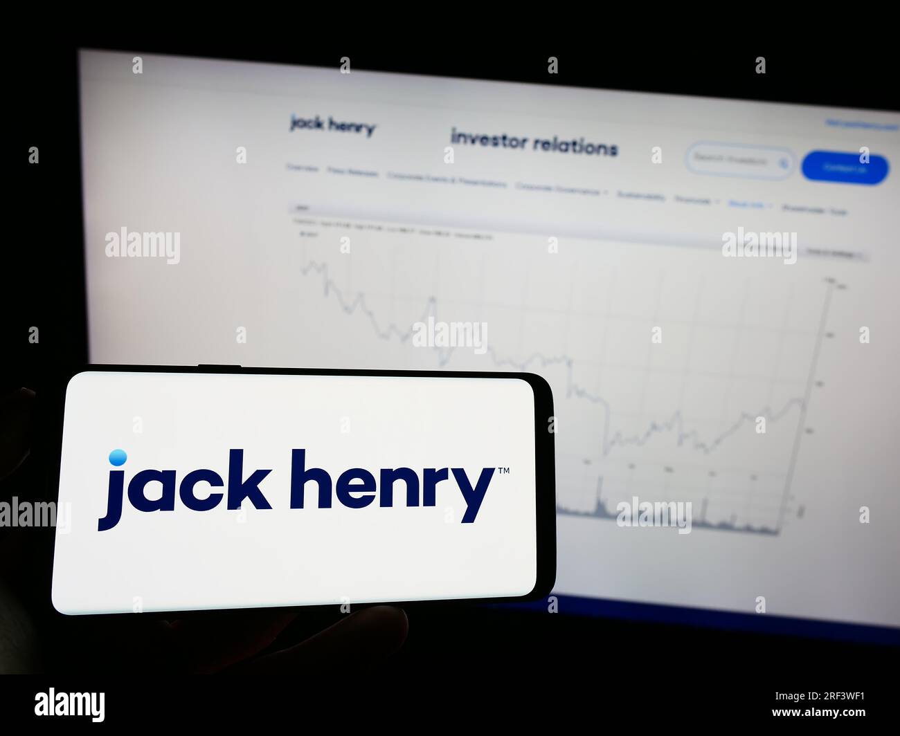 Personne détenant un téléphone portable avec le logo de la société financière américaine Jack Henry Associates Inc. Sur l'écran devant la page Web. Concentrez-vous sur l'affichage du téléphone. Banque D'Images