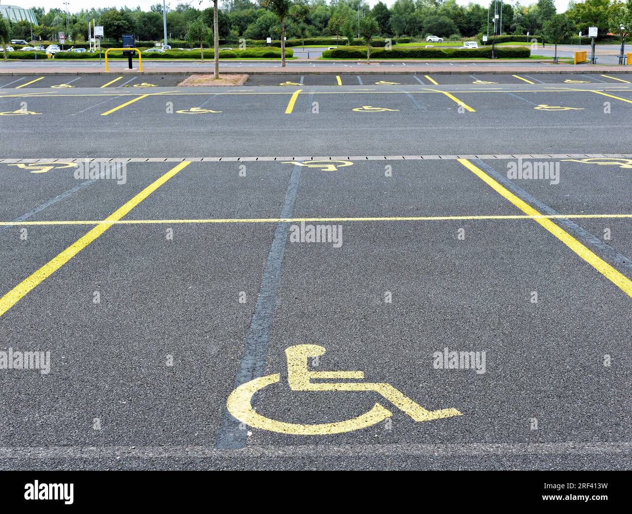 parking avec places de parking réservées aux personnes à mobilité réduite affichant le logo peint en orange sur le sol Banque D'Images