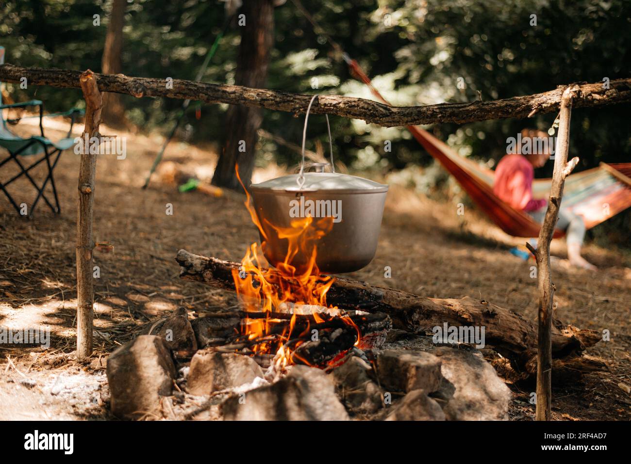 Voyage une bouilloire sur un feu brûlant sur la rivière et coucher de soleil backgroun. Cuisiner sur un feu de camp. Banque D'Images