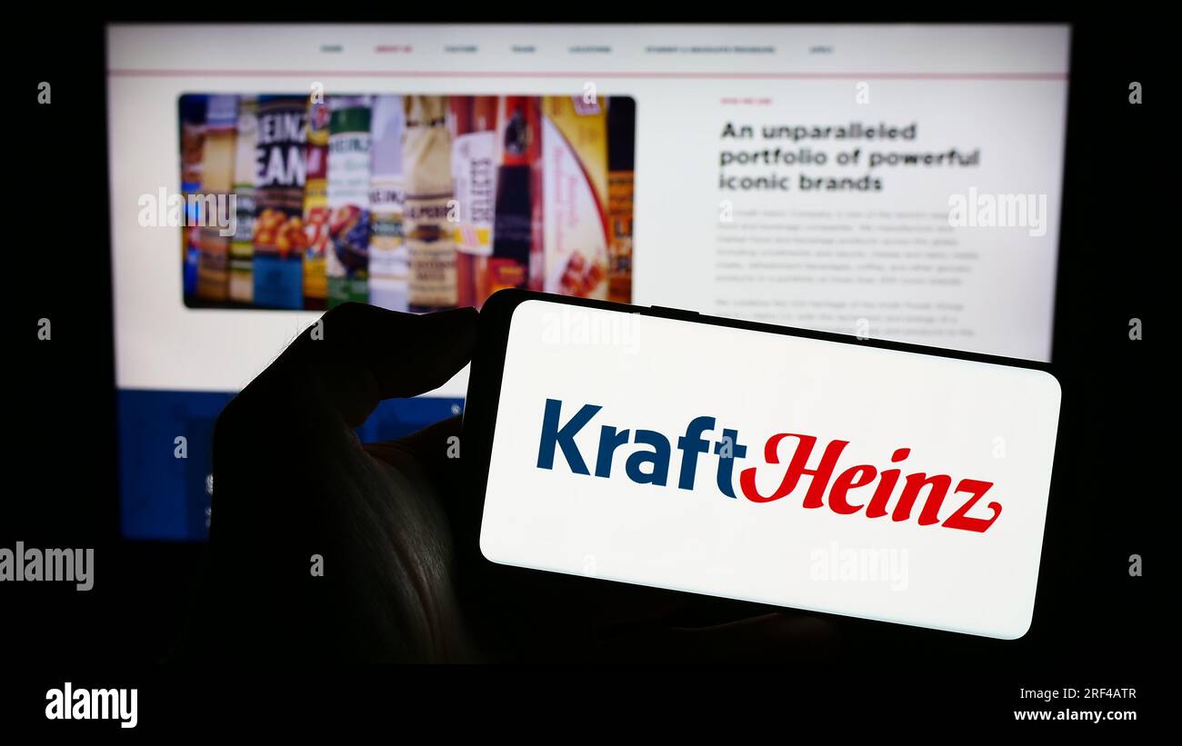 Personne détenant un téléphone cellulaire avec le logo de l'entreprise américaine Kraft Heinz Company (KHC) sur l'écran devant la page Web. Concentrez-vous sur l'affichage du téléphone. Banque D'Images