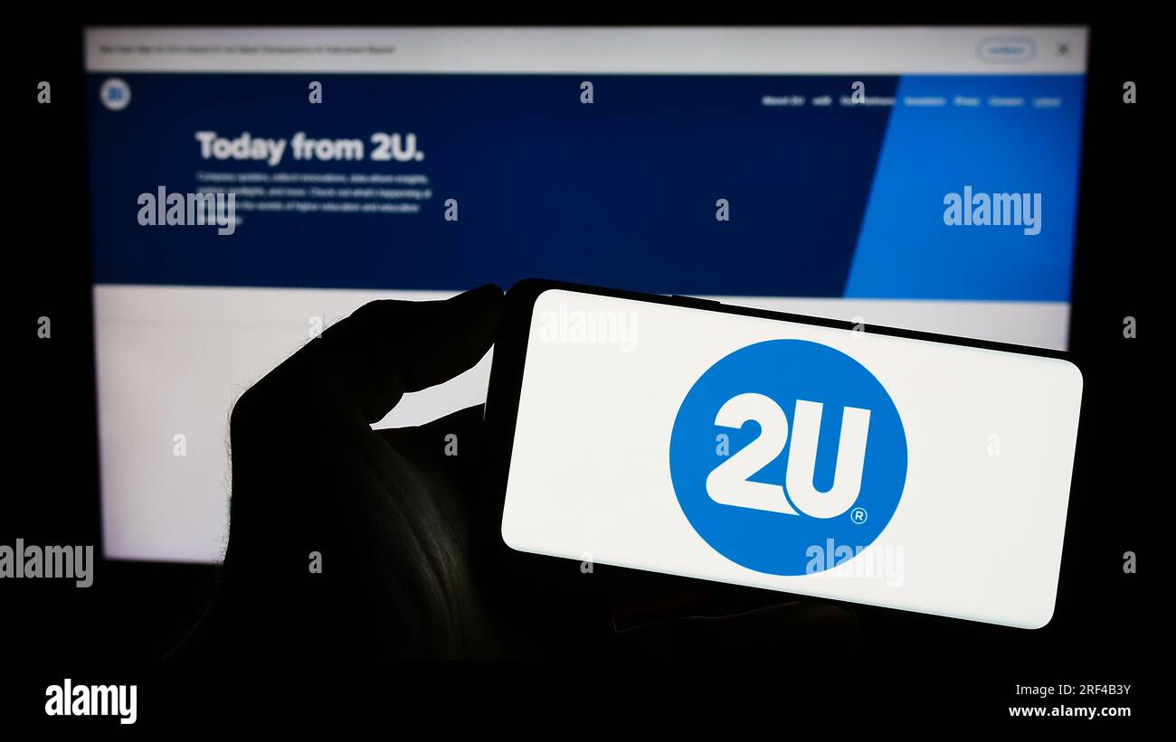 Personne tenant un smartphone avec le logo de la société américaine de technologie éducative 2U Inc. Sur l'écran devant la page Web. Concentrez-vous sur l'affichage du téléphone. Banque D'Images
