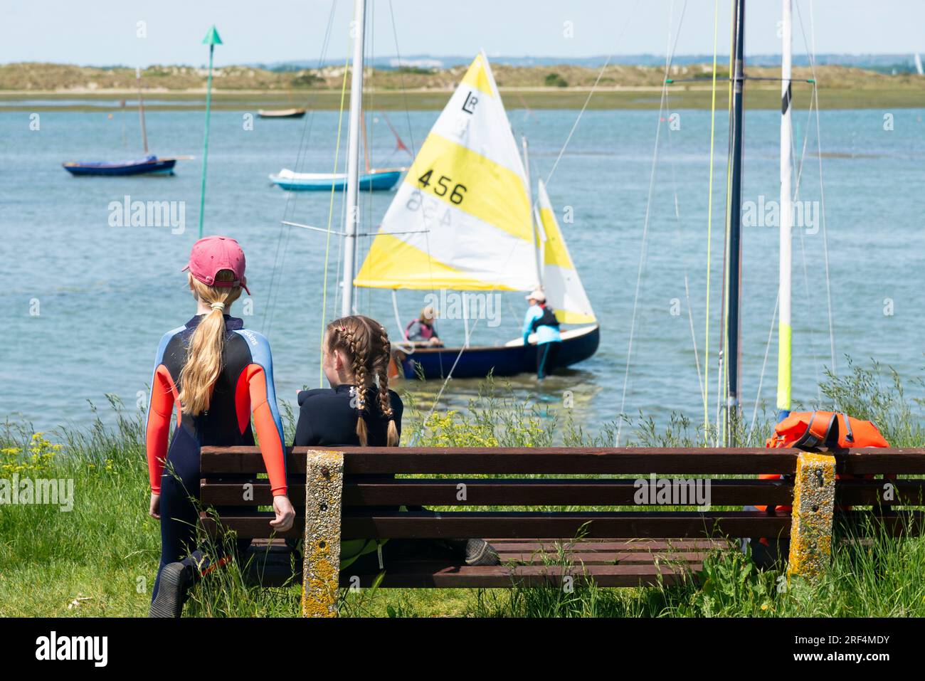 Deux enfants en bord de mer à West Wittering avec une écharpe de la rivière Lymington se préparant à aller naviguer en arrière-plan. West Sussex, Angleterre Banque D'Images