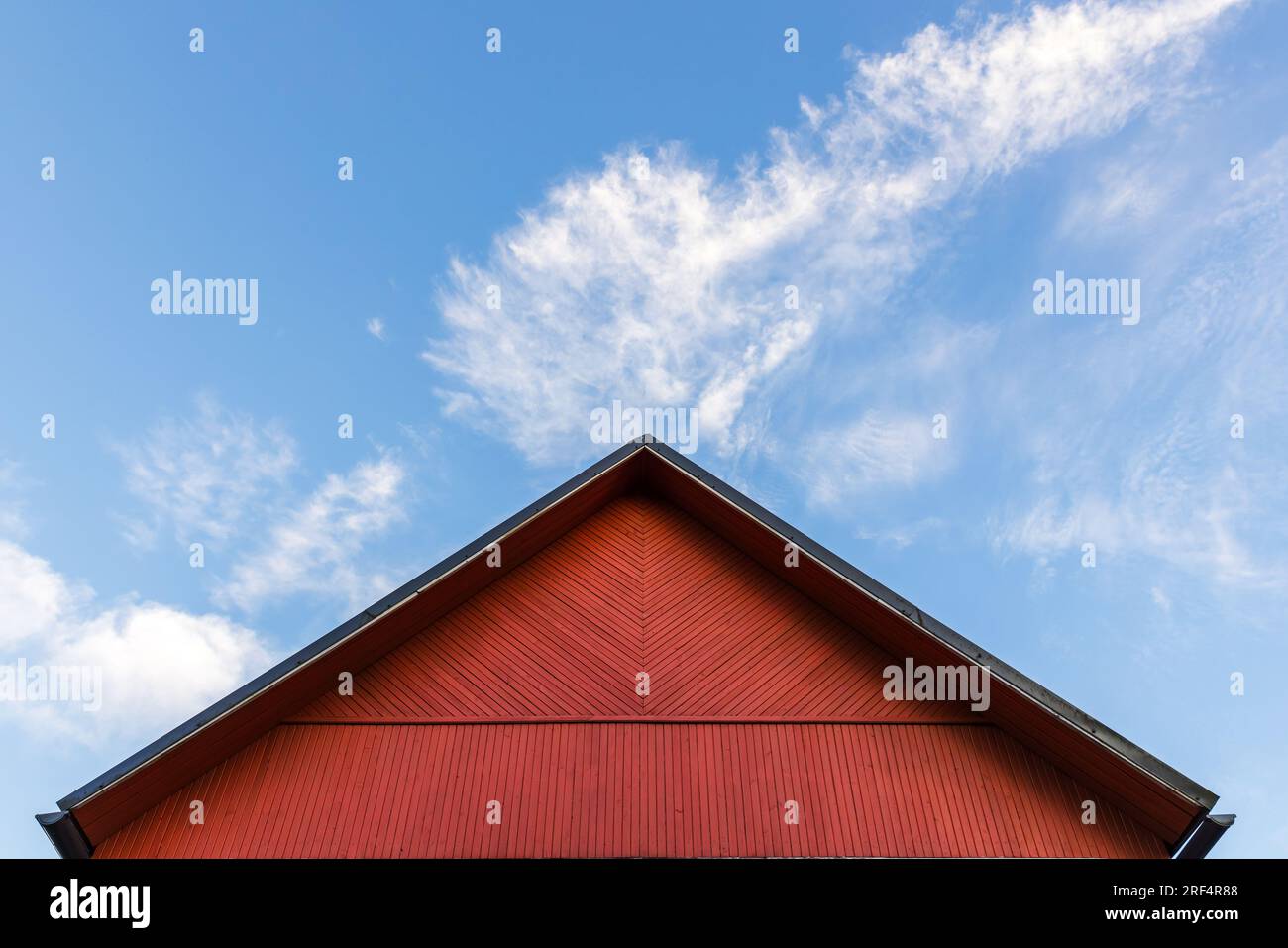 Le pignon en bois rouge est sous un ciel nuageux bleu sur un fond d'architecture scandinave rurale de jour Banque D'Images
