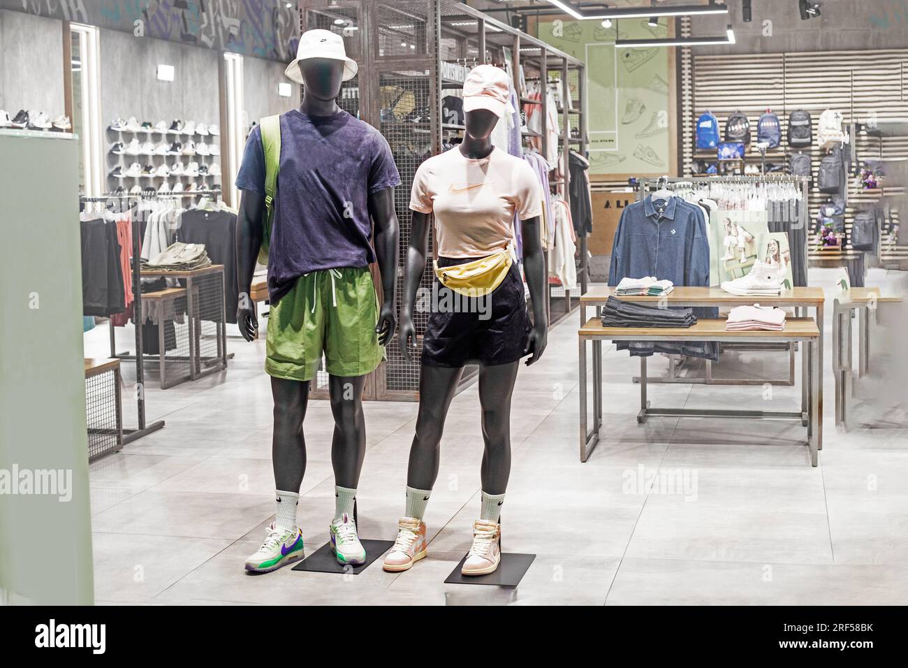 mannequin homme et femme à peau foncée en vêtements de sport et casquettes dans une vitrine. mode décontracté Banque D'Images
