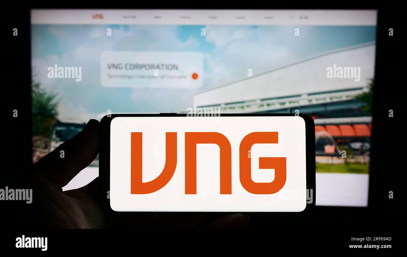 Personne tenant le smartphone avec le logo de la société technologique vietnamienne VNG Corporation sur l'écran en face du site Web. Concentrez-vous sur l'affichage du téléphone. Banque D'Images