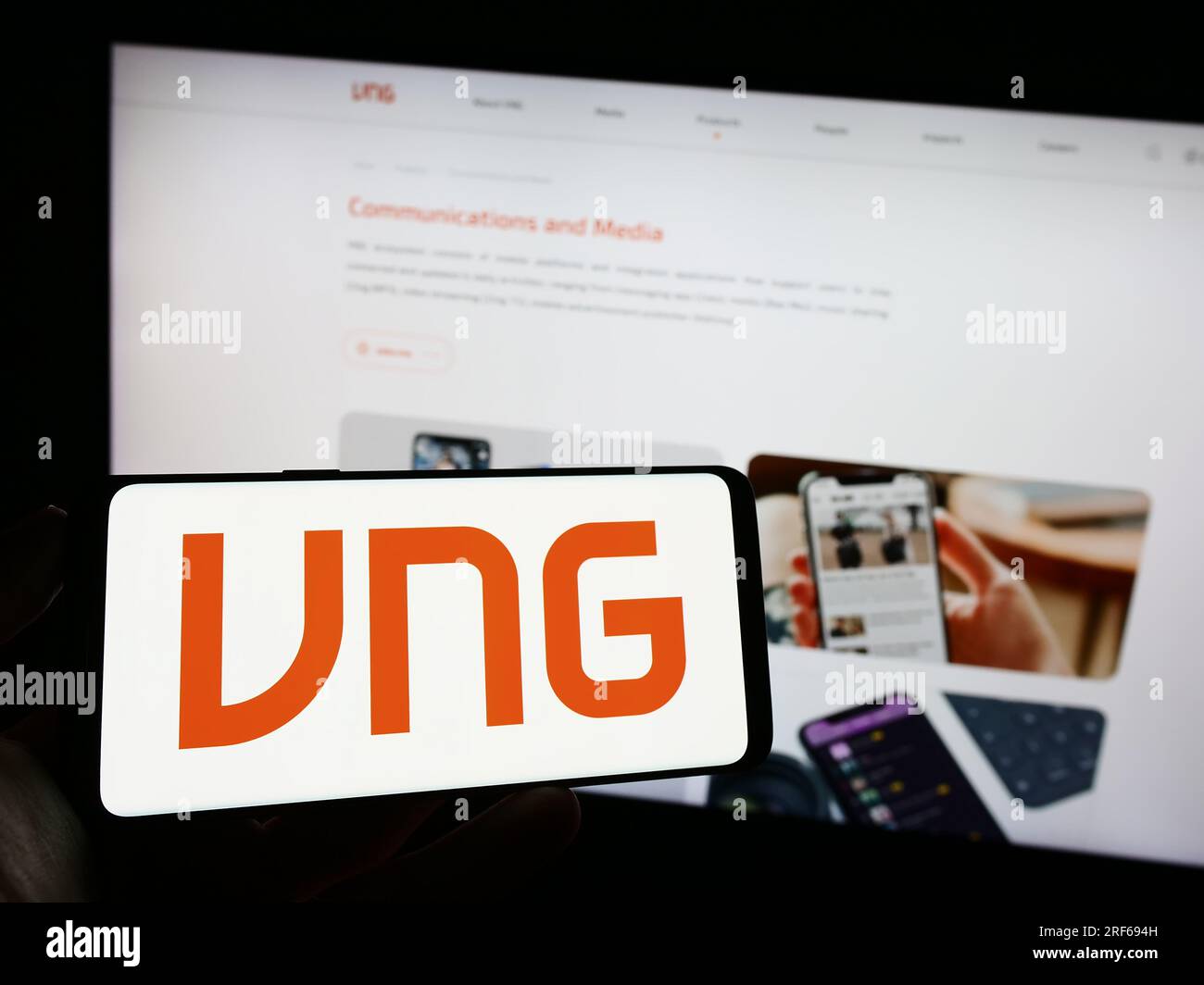 Personne tenant un téléphone portable avec le logo de la société technologique vietnamienne VNG Corporation sur l'écran devant la page Web. Concentrez-vous sur l'affichage du téléphone. Banque D'Images