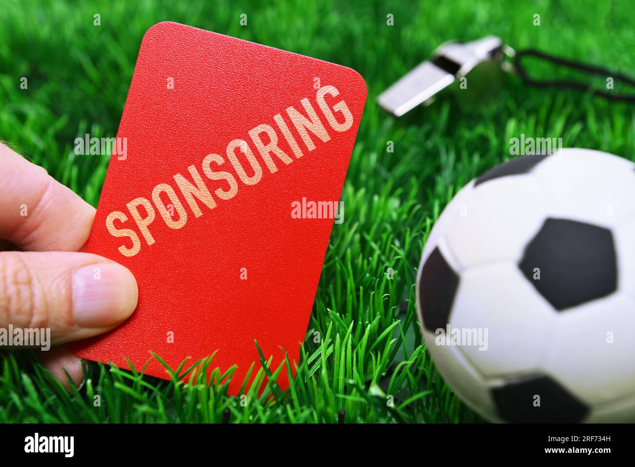 FOTOMONTAGE, Hand hält rote Karte mit Aufschrift sponsoring auf Fußballrasen, Symbolfoto Kündigung von Sponsoring-Verträgen Banque D'Images