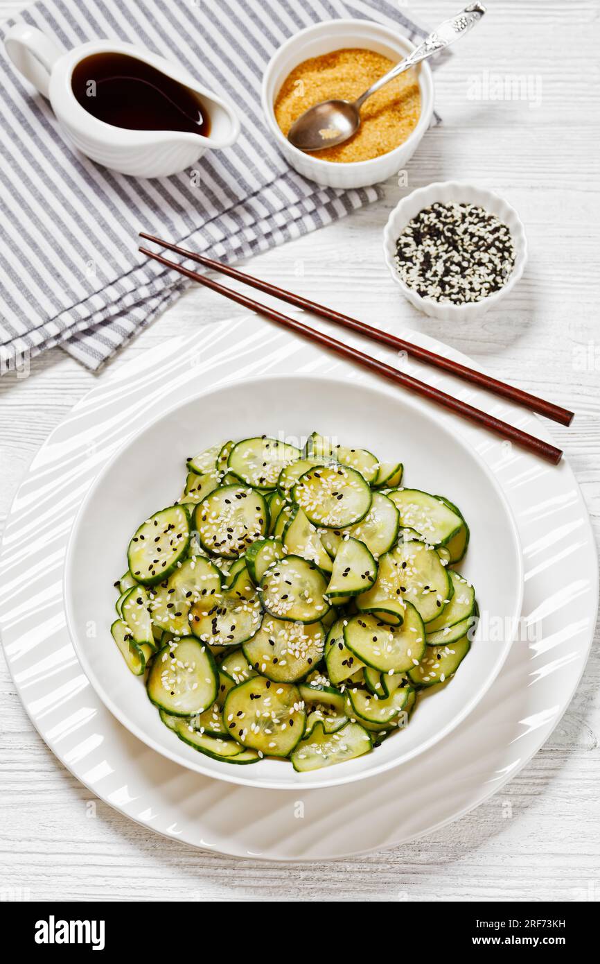 Sunomono, salade japonaise de concombres, tranches de concombres avec sauce asiatique de soja, vinaigre de riz, huile de sésame et sucre dans un bol blanc avec baguettes Banque D'Images
