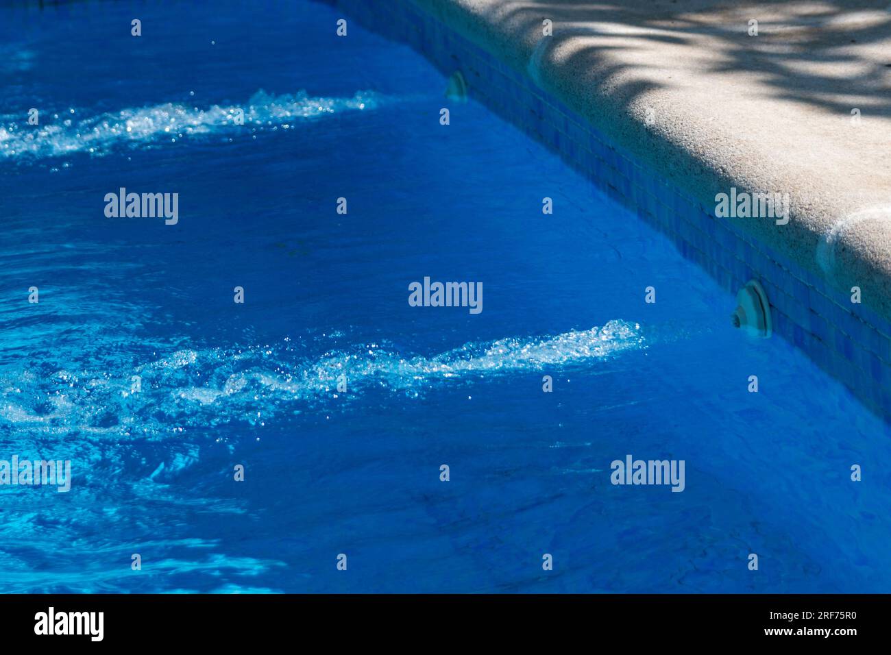 Détails dans une piscine, qu'il s'agisse de la chaise avec son parasol, de l'échelle en acier inoxydable ou des jets de la station d'épuration Banque D'Images