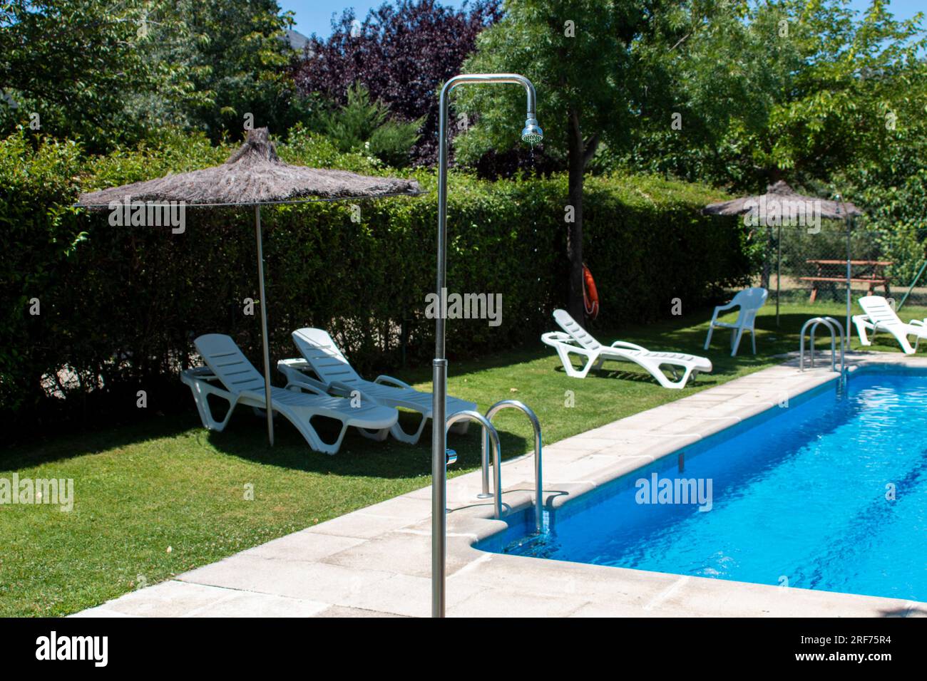 Détails dans une piscine, qu'il s'agisse de la chaise avec son parasol, de l'échelle en acier inoxydable ou des jets de la station d'épuration Banque D'Images