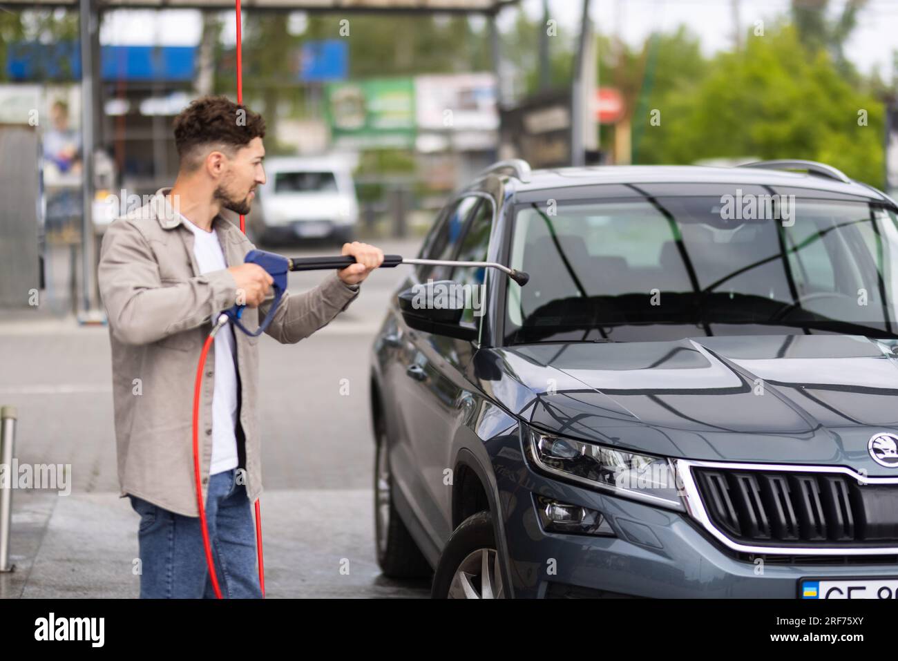 L'homme lave sa voiture sous l'eau sous pression à l'extérieur Banque D'Images