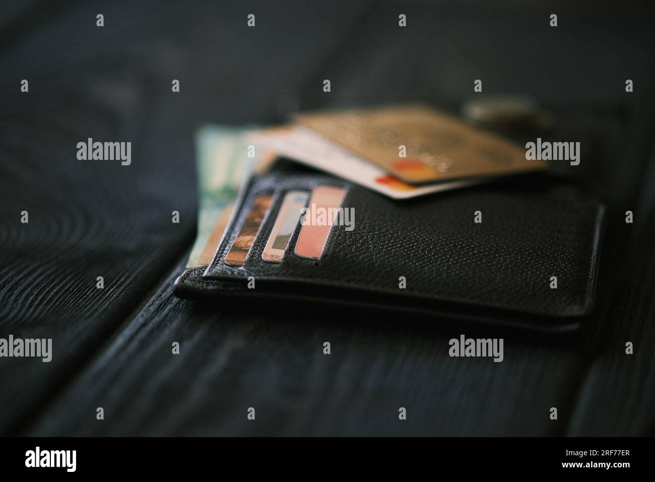 Un téléphone portable posé sur un sac à main en cuir et une petite pile de pièces de monnaie sur une table en bois noir, concept financier Banque D'Images