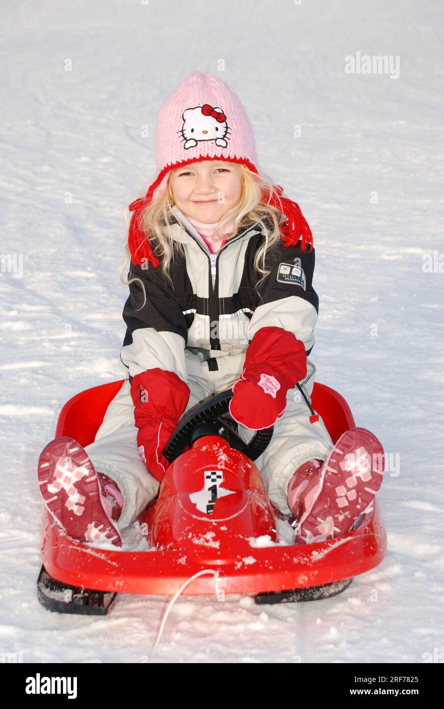 Blondes Mädchen in Winterkleidung fährt einen Bob im Schnee, 5-6, Jahre, Banque D'Images