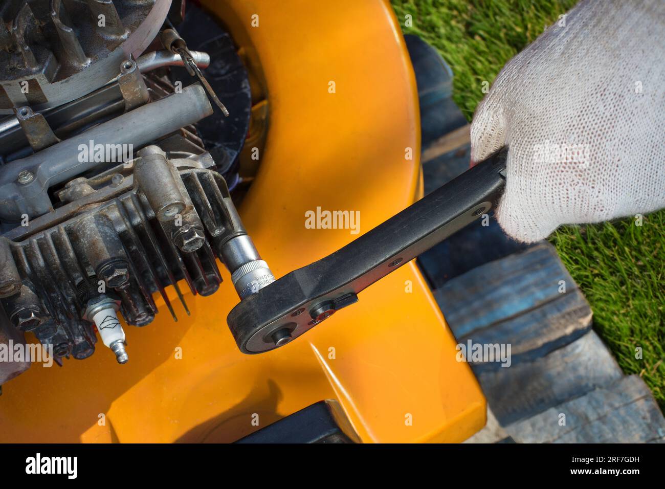 Gros plan détaillé d'un homme qui répare une tondeuse à gazon avec expertise, mettant en évidence les subtilités de l'entretien de l'équipement de tonte. Banque D'Images