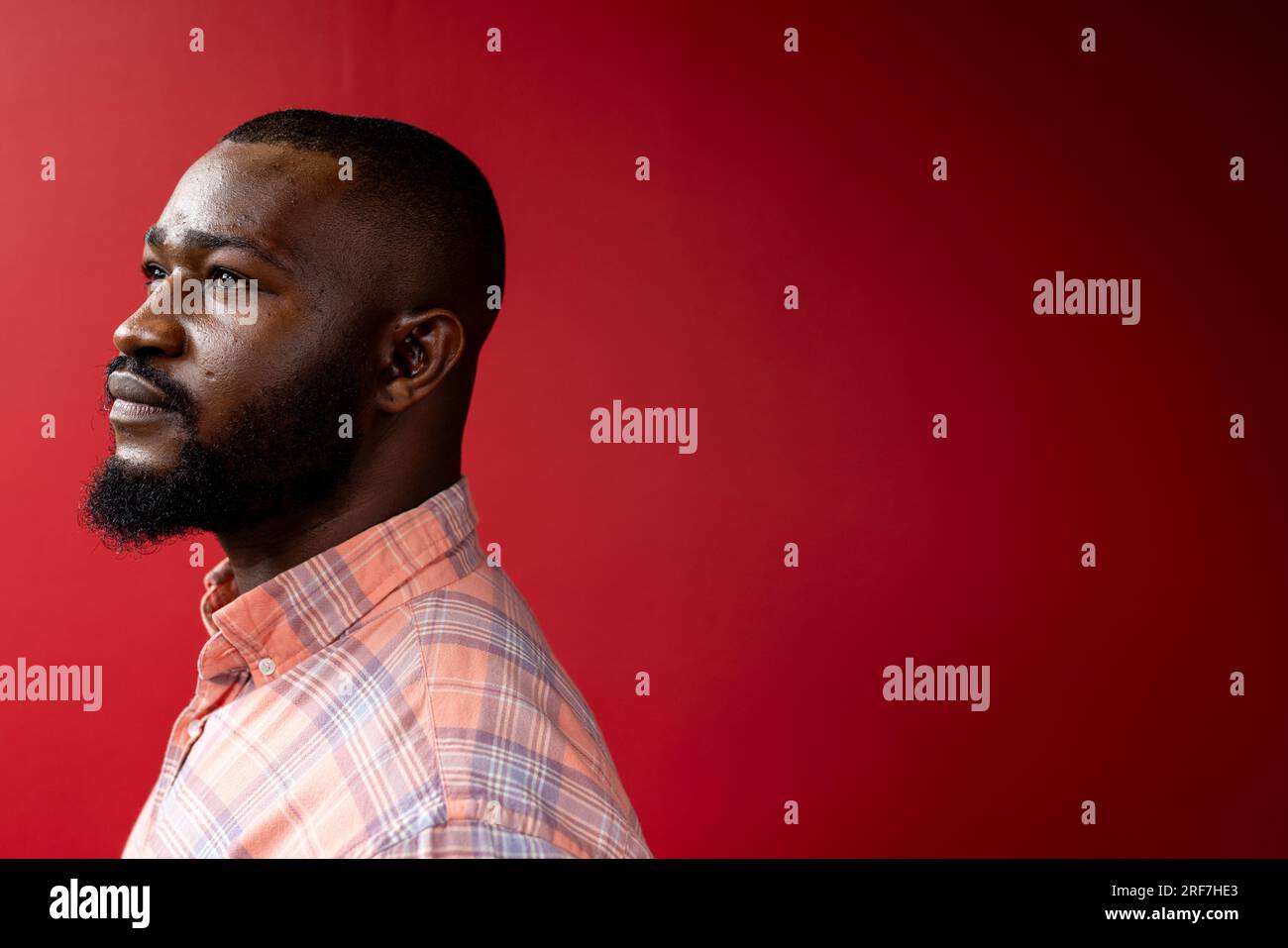 Vue de profil latérale de l'homme d'affaires afro-américain sur fond rouge, espace de copie Banque D'Images