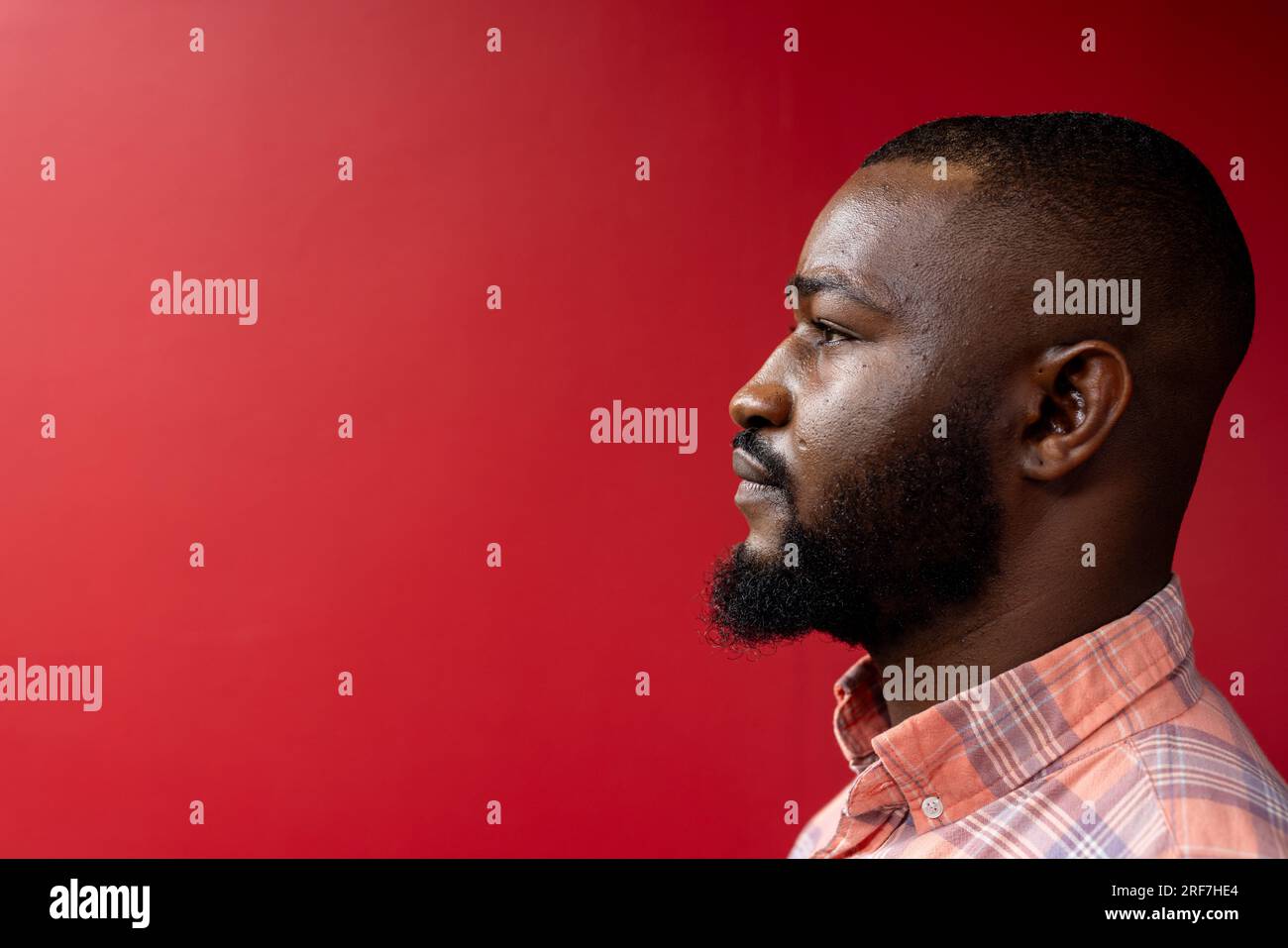 Vue de profil latérale de l'homme d'affaires afro-américain sur fond rouge, espace de copie Banque D'Images