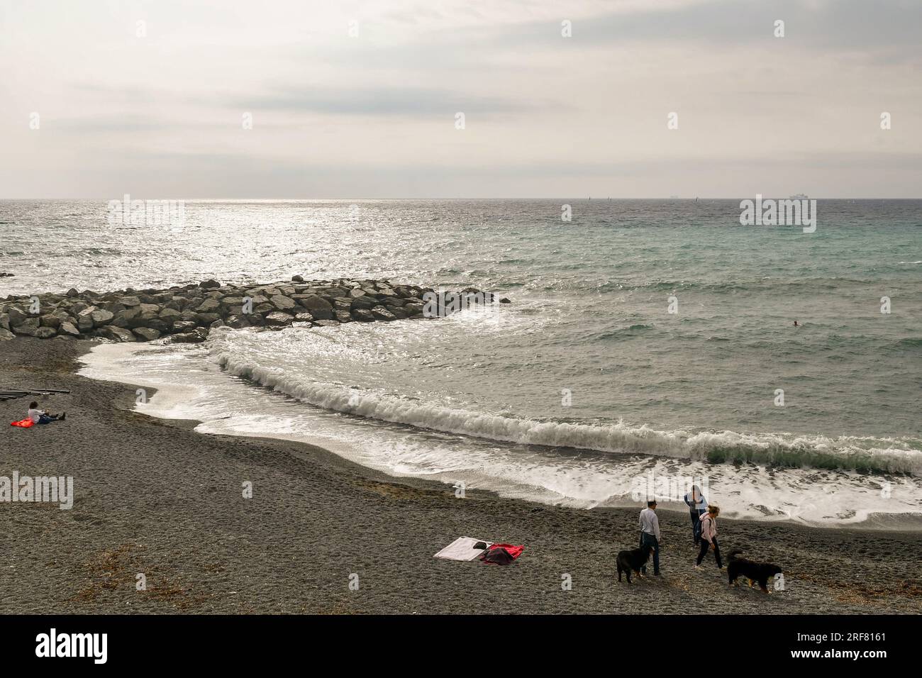 Vue surélevée sur la plage hors saison de Vernazzola, un petit village de pêcheurs à une courte distance de Gênes, avec des gens et des chiens, Ligurie, Italie Banque D'Images