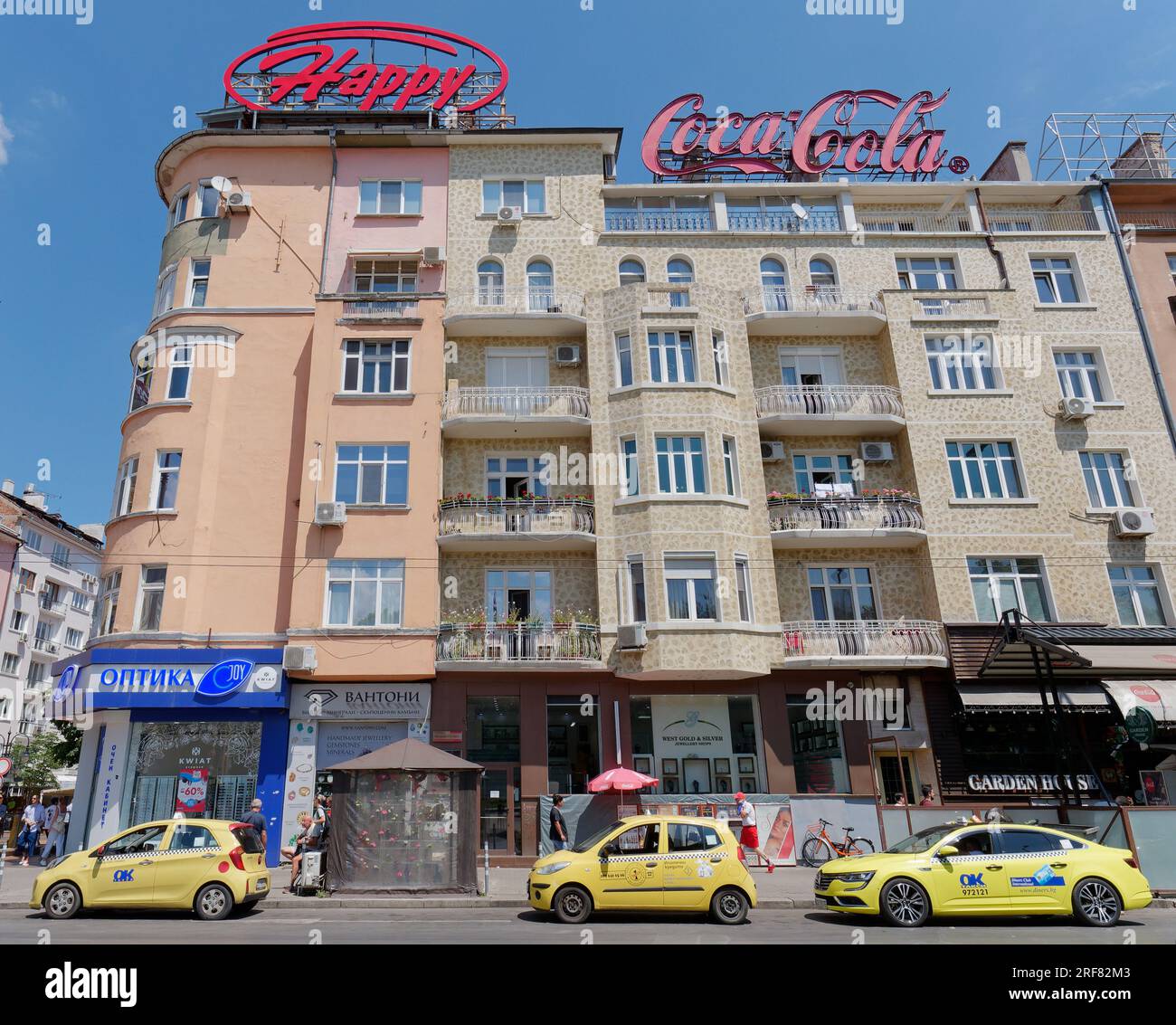 Taxis jaunes à l'extérieur d'un immeuble jaune et beige à plusieurs étages avec des magasins dans la ville de Sofia, Bulgarie. 01 août 2023. Banque D'Images