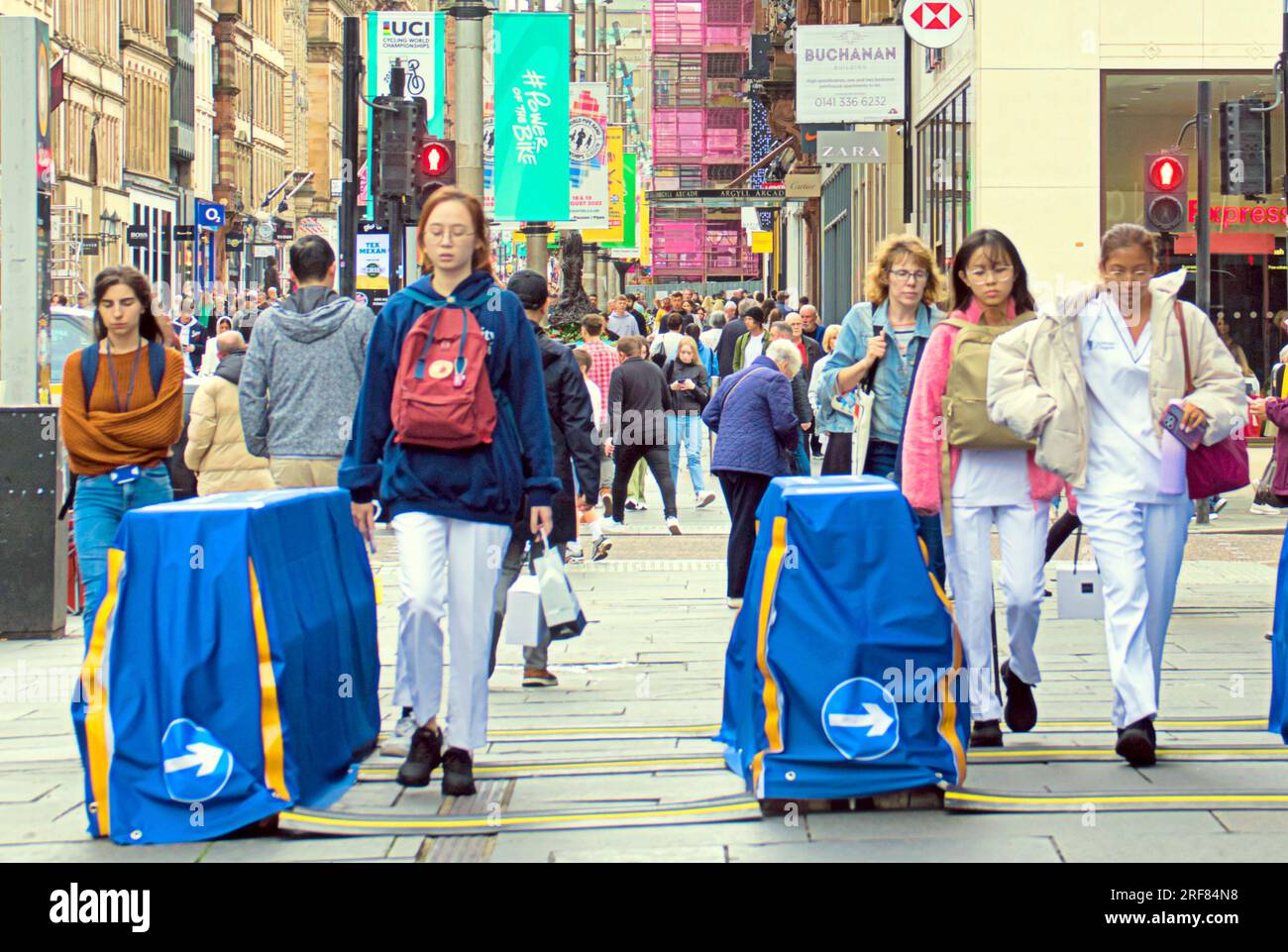 Glasgow, Écosse, Royaume-Uni 31 juillet 2023. Des barrières anti-terroristes UCI sont installées pour les championnats du monde dans les rues de la ville et canalisent les foules pour la vérification des bagages avec la circulation et les barrières. Les gens utilisent les barrières de contrôle de foule de la rue. . Crédit Gerard Ferry/Alamy Live News Banque D'Images