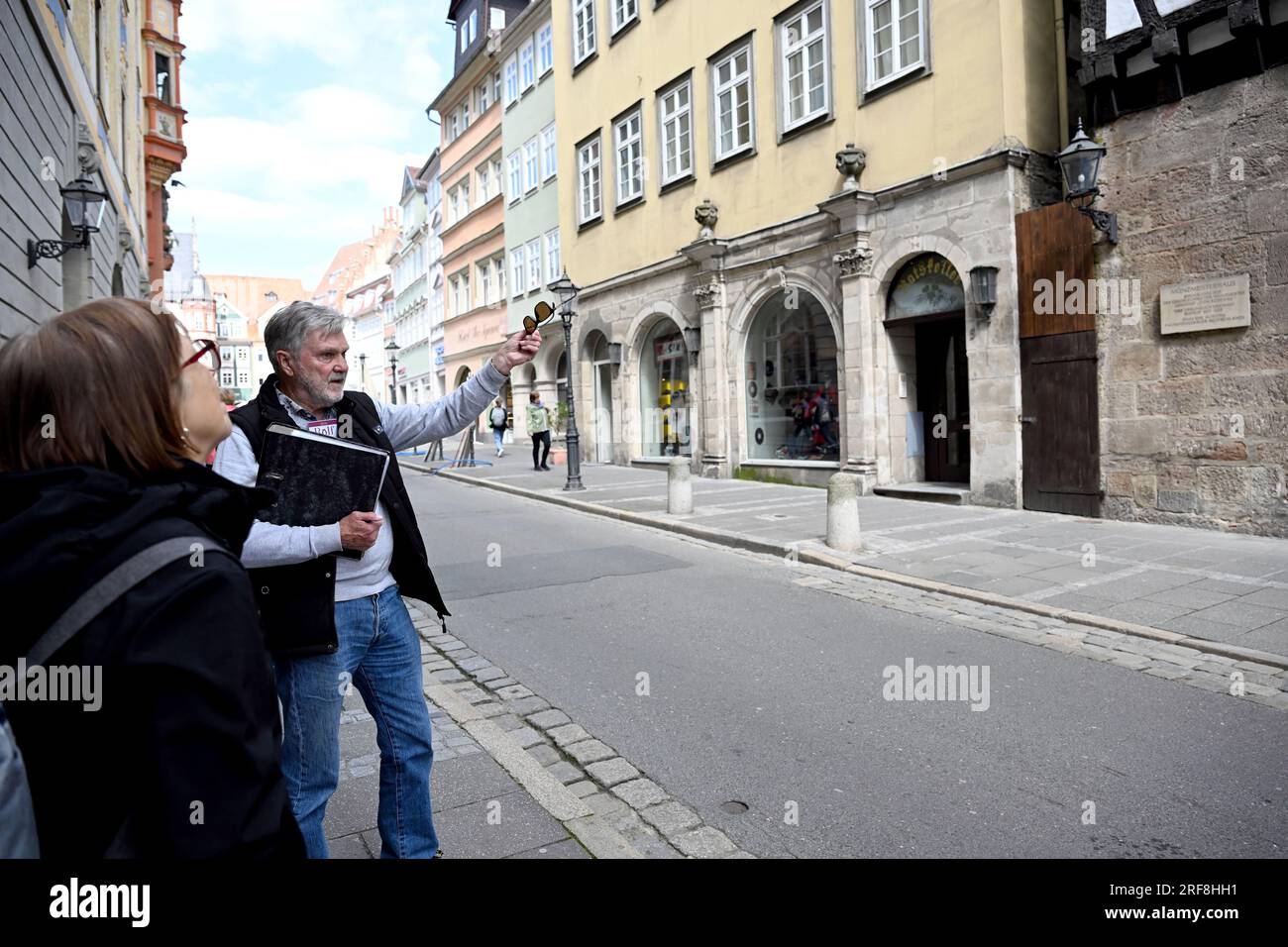 Coburg, Allemagne. 17 mai 2023. Rolf Metzner, Greeter de Coburg, montre à un touriste la Maison du Maître de la monnaie à Coburg. Dans sa main, il tient un dossier avec des photos historiques. Dans de petites promenades personnelles - ce que l'on appelle des «saluts» - les habitants guident volontairement les visiteurs à travers leur ville sur demande. Crédit : Pia Bayer/dpa/Alamy Live News Banque D'Images