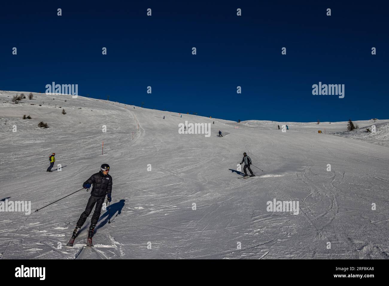 Falcade, Italie - 15 février 2023 : piste de ski avec skieur sous ciel bleu. Les gens descendent les montagnes enneigées à skis. Groupe de skieurs sur une piste de ski Banque D'Images
